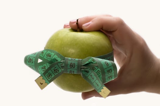 Green apple with measuring tape in a hand.