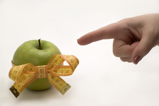 Green apple with measuring tape in a hand.