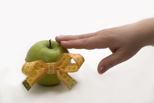 Green apple with measuring tape in a hand.