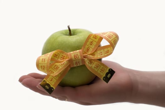Green apple with measuring tape in a hand.