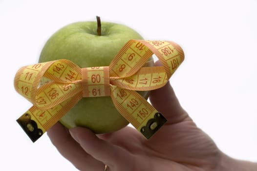 Green apple with measuring tape in a hand.