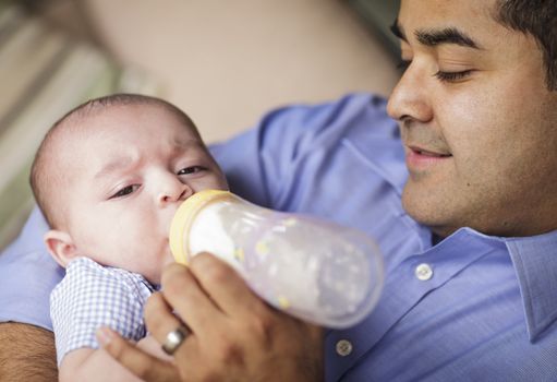 Happy Hispanic Father Bottle Feeding His Very Content Son.