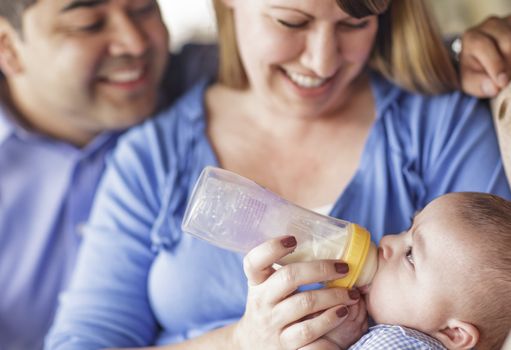 Happy Attractive Mixed Race Couple Bottle Feeding Their Baby Son.