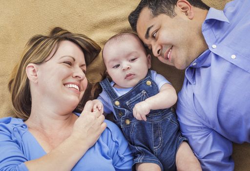 Mixed Race Family with Baby Boy Playing Face Up on the Blanket.