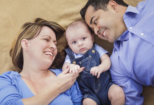 Mixed Race Family with Baby Boy Playing Face Up on the Blanket.