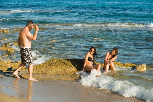 Typically persistent guy harassing sunbathing girls on the beach