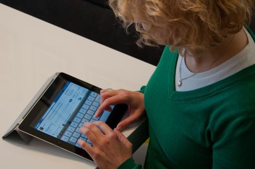 Stuttgart, Germany - January 29, 2012: Close up of an Apple iPad screen showing the Facebook website with a middle-aged female typing a status update