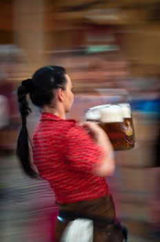 STUTTGART, GERMANY - SEPTEMBER 25 : A young waitress is serving beer mugs by the "Mass" (1 liter pitchers) at the Cannstatter Wasen, the Swabian version of the Bavarian Oktoberfest, wearing the traditional costume on September 25, 2011 in Suttgart, Germany.