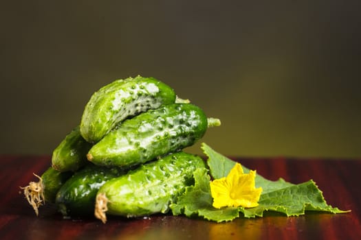 Cucumbers with flowers and green leaveas on the table.