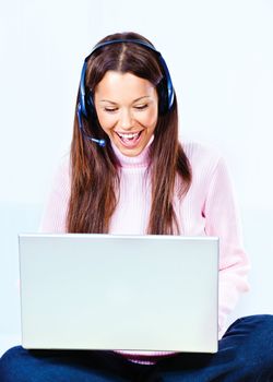 Happy young woman with headphones and  laptop at home