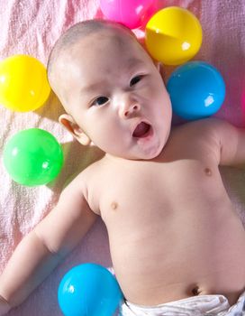 A happy 3 months old baby in a bath of balls.