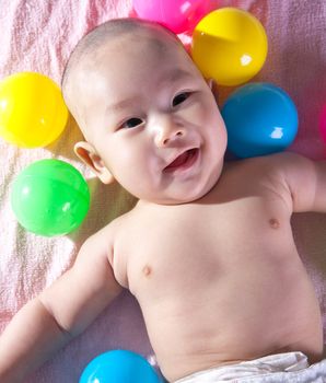 A happy 3 months old baby in a bath of balls.