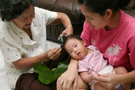 6 month old Asian baby girl having a haircut.