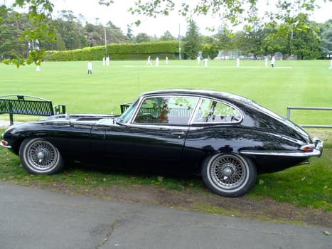 Old Black Jaguar car at a cricket match