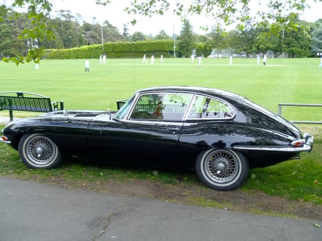 Old Black Jaguar car at a cricket match