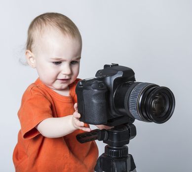 young child with digital SLR camera on neutral background