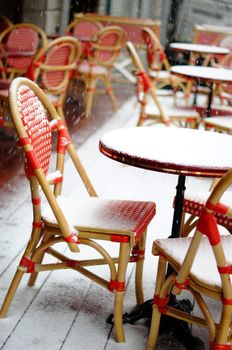 Rare snowy and cold day in Tbilisi. Street red cafe table and chairs covered with snow