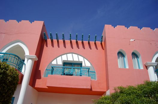 Arabic architecture: red walled villa and blue sky                 