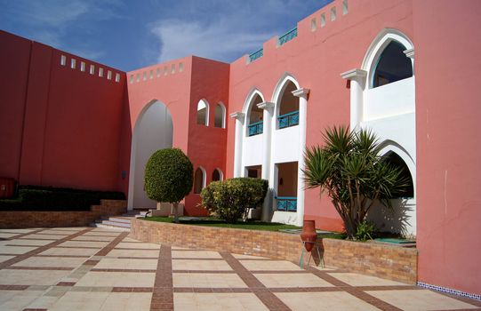 Arabic architecture: Courtyard of mediterranean villa with ceramic tile walkway and blooming bushes in Egypt        