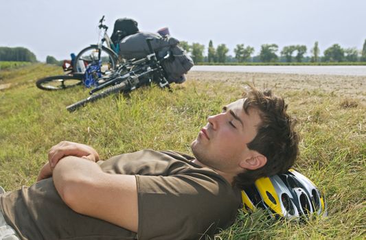 Young cyclist lying on a ground with eyes closed