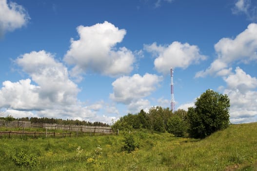 Country landscape with a cellular tower in the distance, cloudy sky