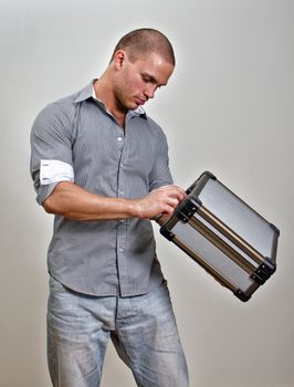 Trendy male holding suitcase. On grey background.