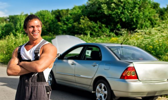 Handsome mechanic on a road near the broken car