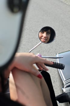 Pretty woman reflection in a motorcycle mirror.