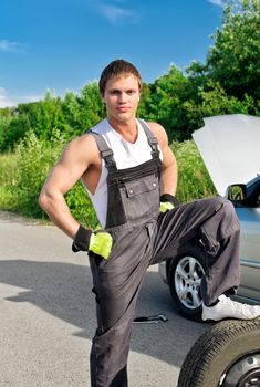 Portrait of a handsome mechanic on a road