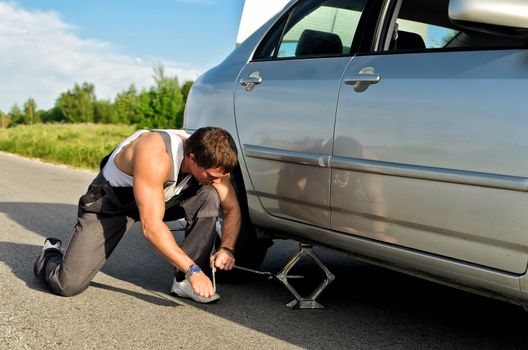 Mechanic lifting a car with jack-screw