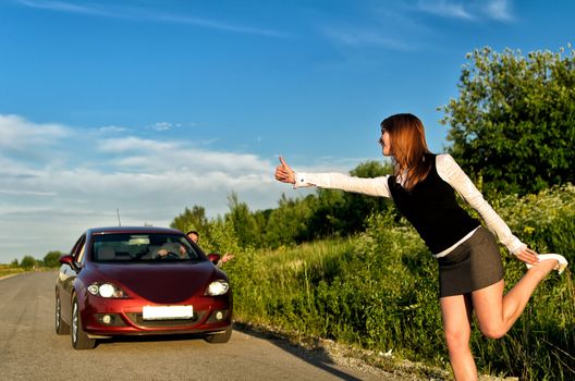 Young pretty girl hitchhiking a red car