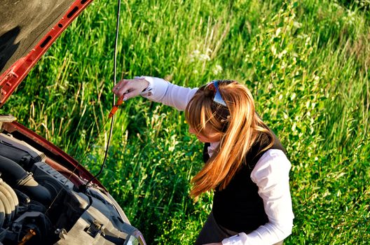 Young girl measures oil level in a car