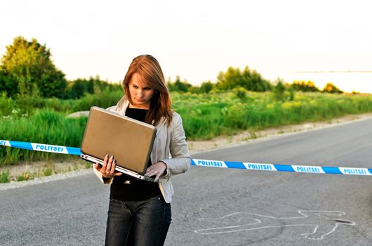 Young criminalist with laptop on a crime scene