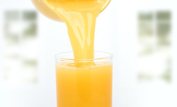 Orange juice flowing to the glass. Windows on a background