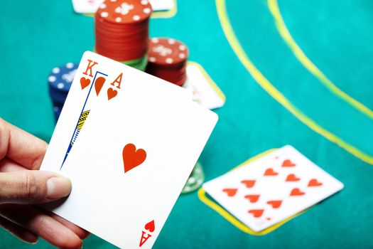 Human hand holding two cards in casino. Poker chips on a background
