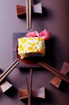 Close up top view on the Japan rolled sushi with caviar on the table and numerous chopsticks. Vertical photo with shallow depth of field