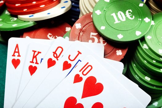 Royal flush and poker chips on a green table of casino
