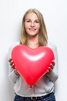 Smiling caucasian woman holding a red heart balloon