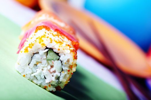 Close-up horizontal photo of the rolled sushi with rice and cucumber on the table. Vibrant color and shallow depth of field for natural view