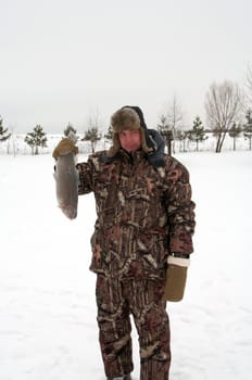 The smiling man holds the caught trout.