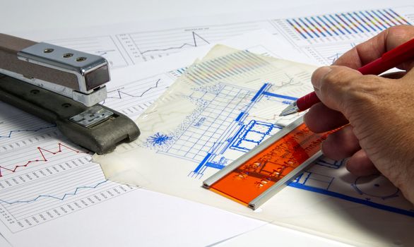 man making diagrams and graphics on  a table with calculator and stapler