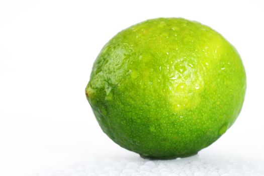 Beautiful studio shot of a fresh and wet lime, with water droplets dripping off it over white, perfect nutrition or diet background.