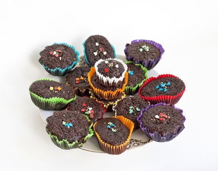 Chocolate muffins with sprinkles in paper cases on the plate