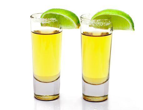 Shot of Gold Tequila with Slice Lime on white background