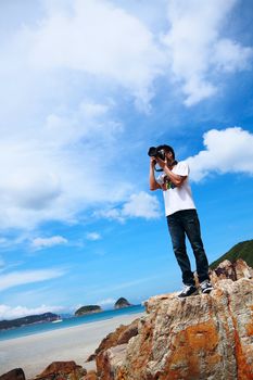 Portrait of a young man standing on a beach with a camera 