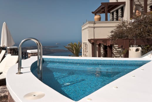 Caldera view in Santorini island with buildings and a small swimming pool in front