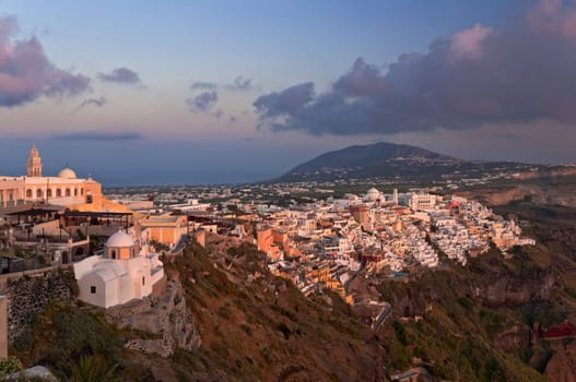Sunset in Thira town with white and orange buildings on the rock