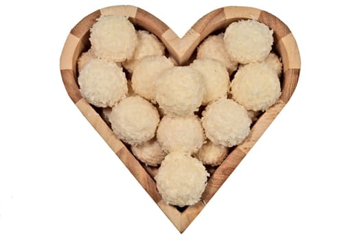 Candy in a wooden box in the shape of a heart isolated on white background. Close-up, top view.