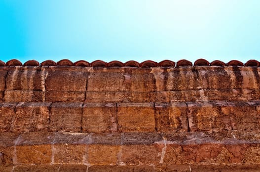 A fragment of an old weathered fence with a tiled cover.