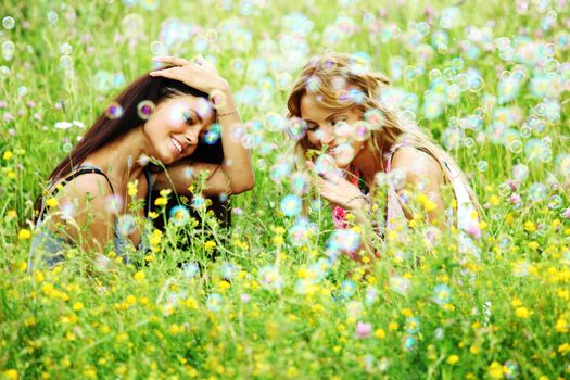 girlfriends on green grass field in soap bubbles